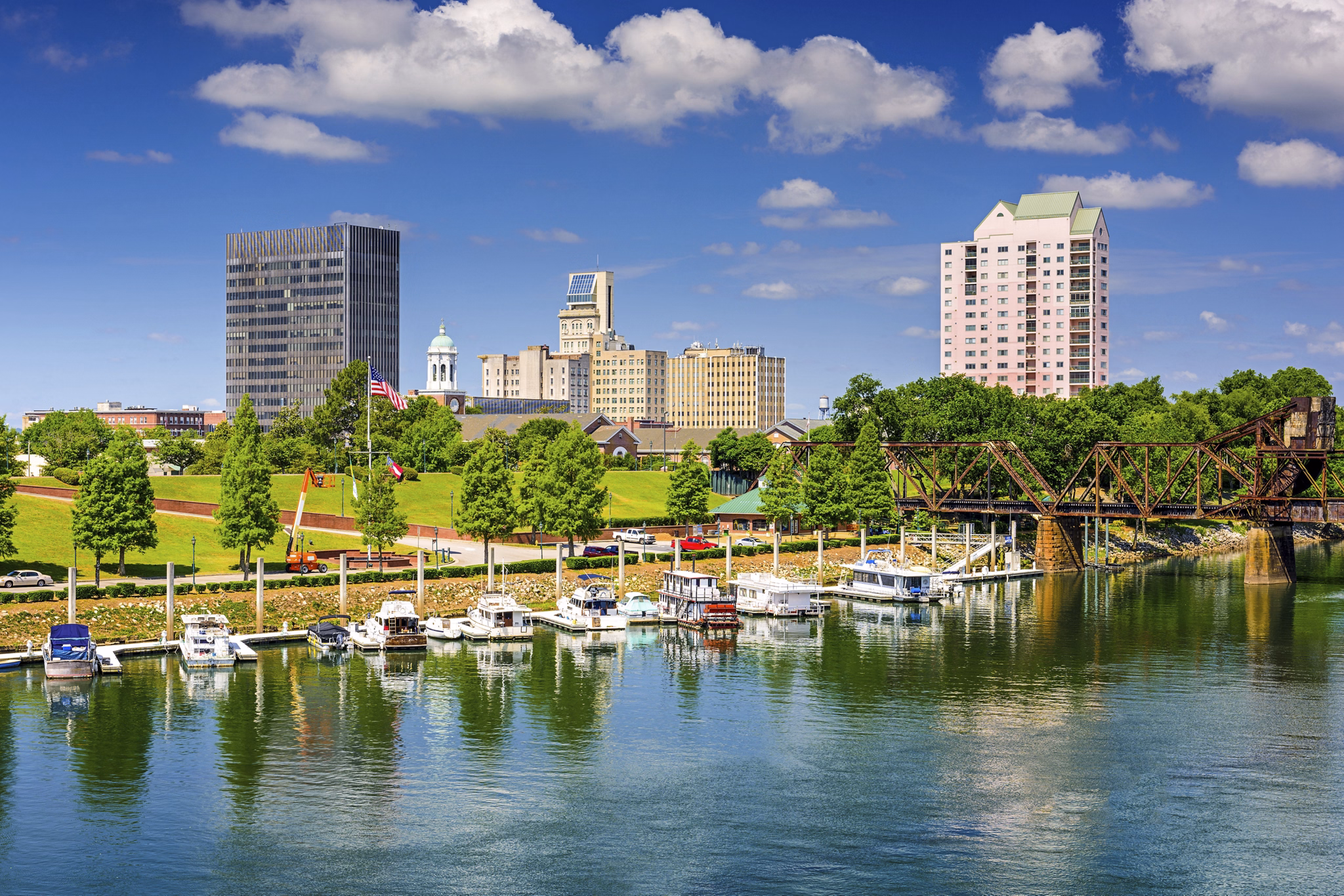 Augusta Metro, GA riverfront with a small marina, park, old railway bridge, and the city skyline.
