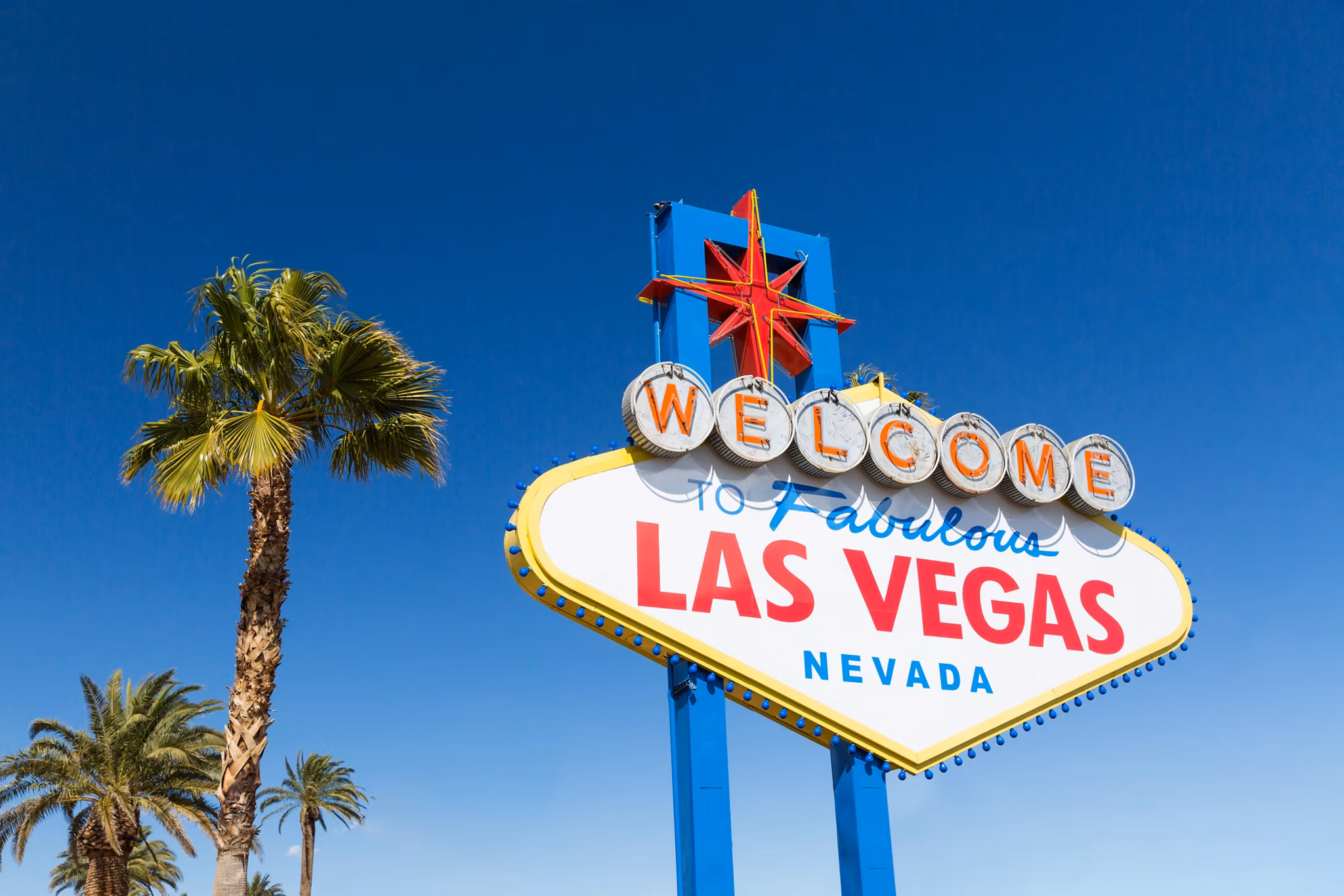 landmarks concept - welcome to fabulous las vegas sign and palm trees over blue sky in united states of america