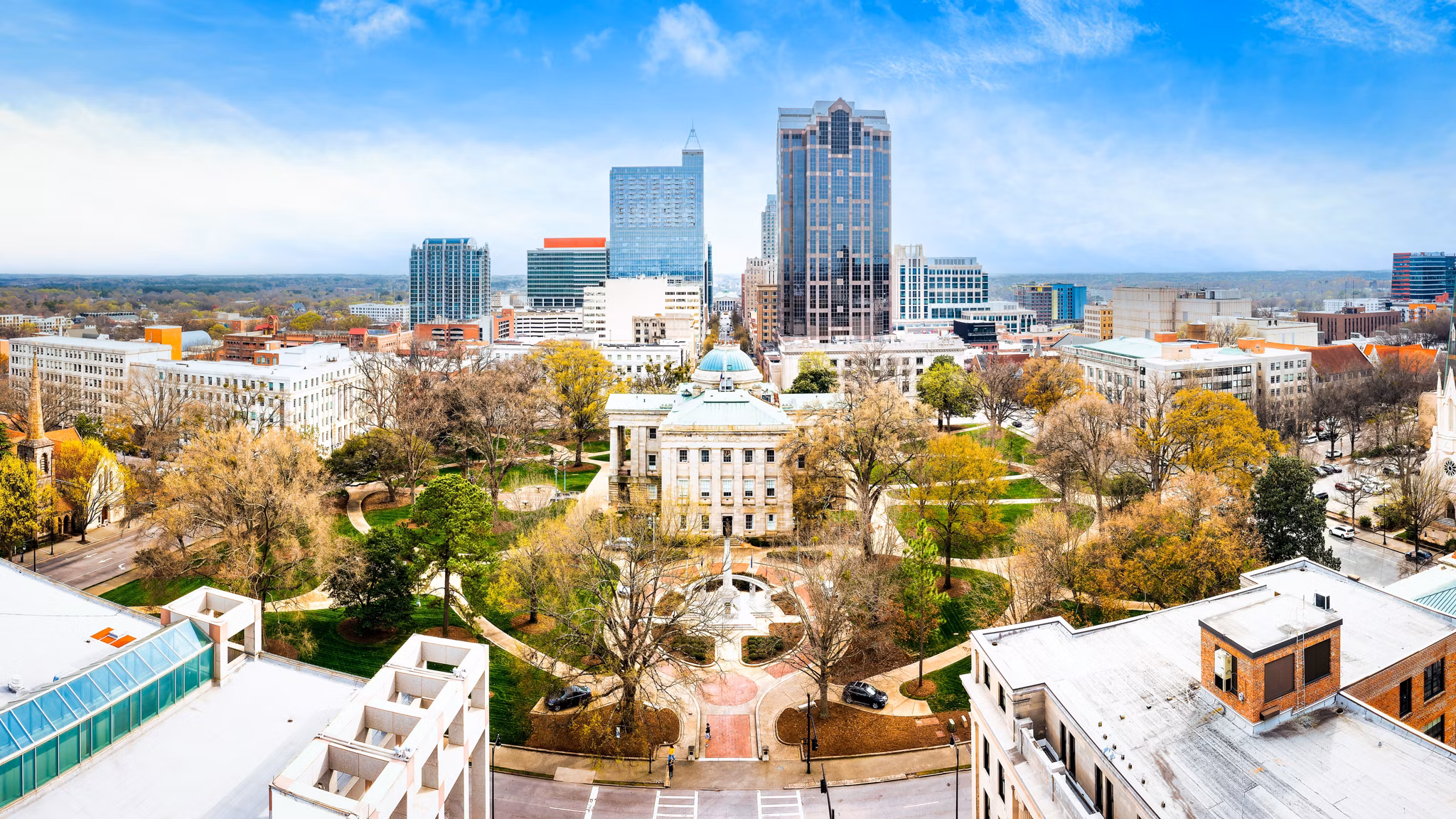 Aerial drone panorama of the historic North Carolina State Capitol building and modern downtown Raleigh city skyline at sunset, Raleigh, North Carolina.