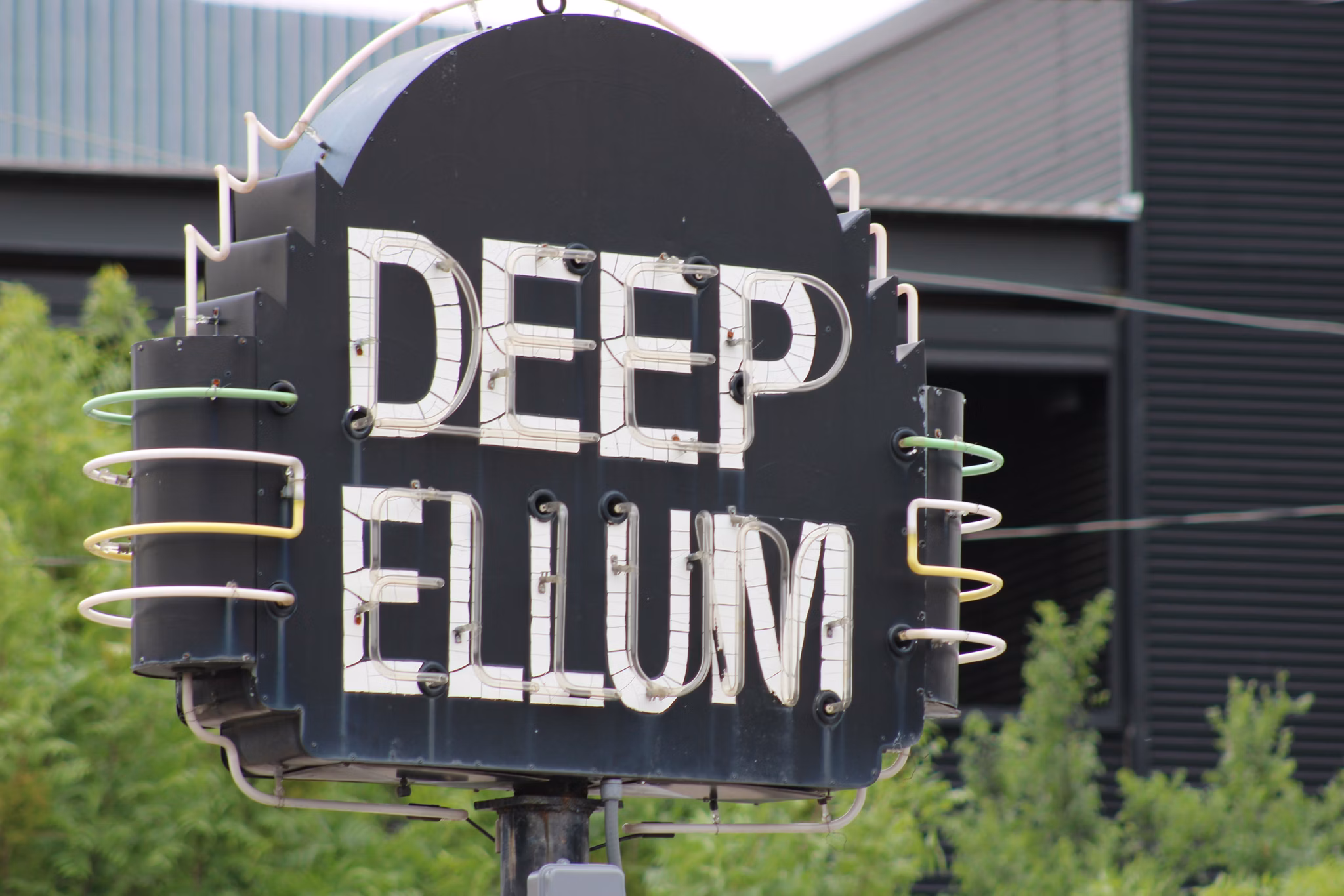 Sign for Deep Ellum, a vibrant neighborhood in Texas, featuring bold letters against a dark background.