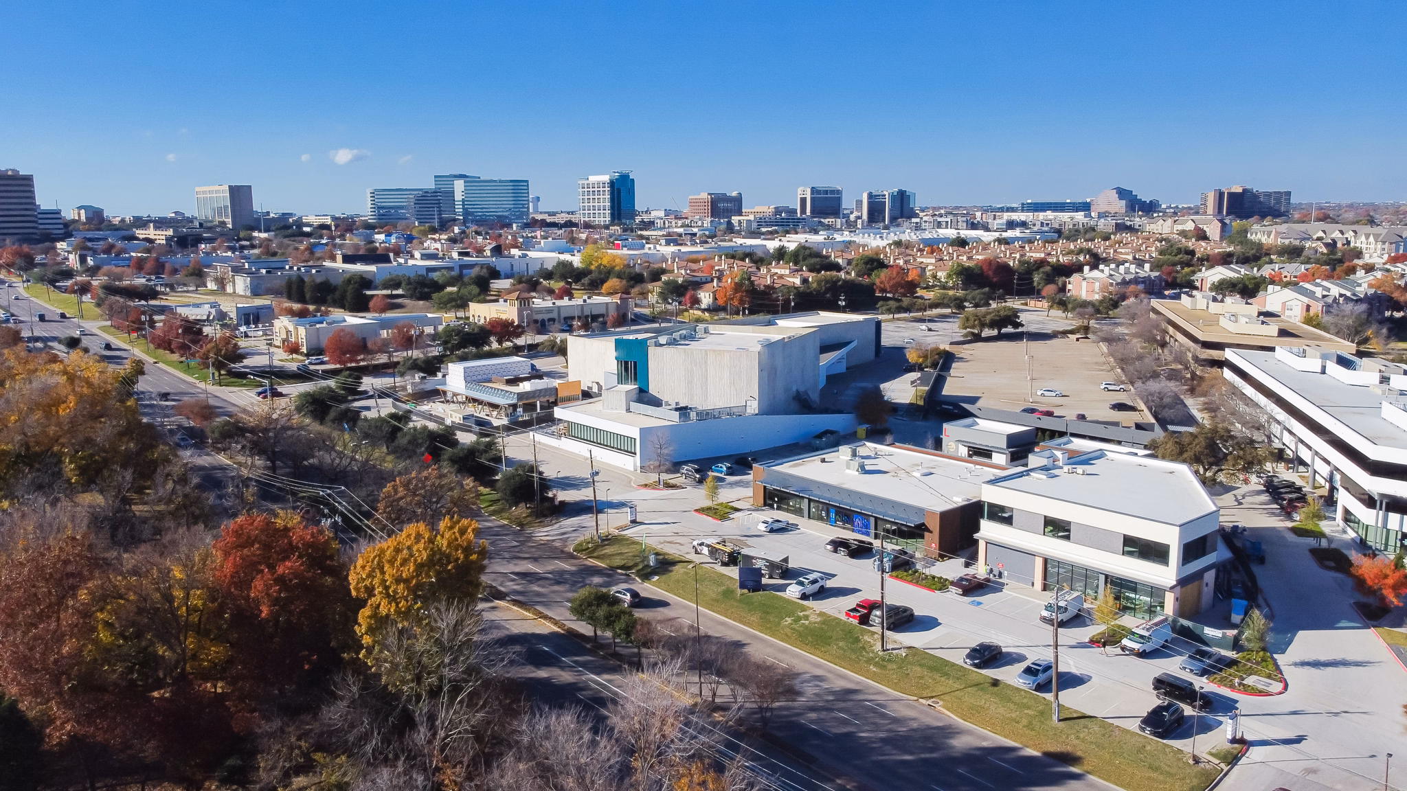 Aerial view of the Far North/Addison neighborhood in Texas, featuring buildings, trees, and clear blue skies.