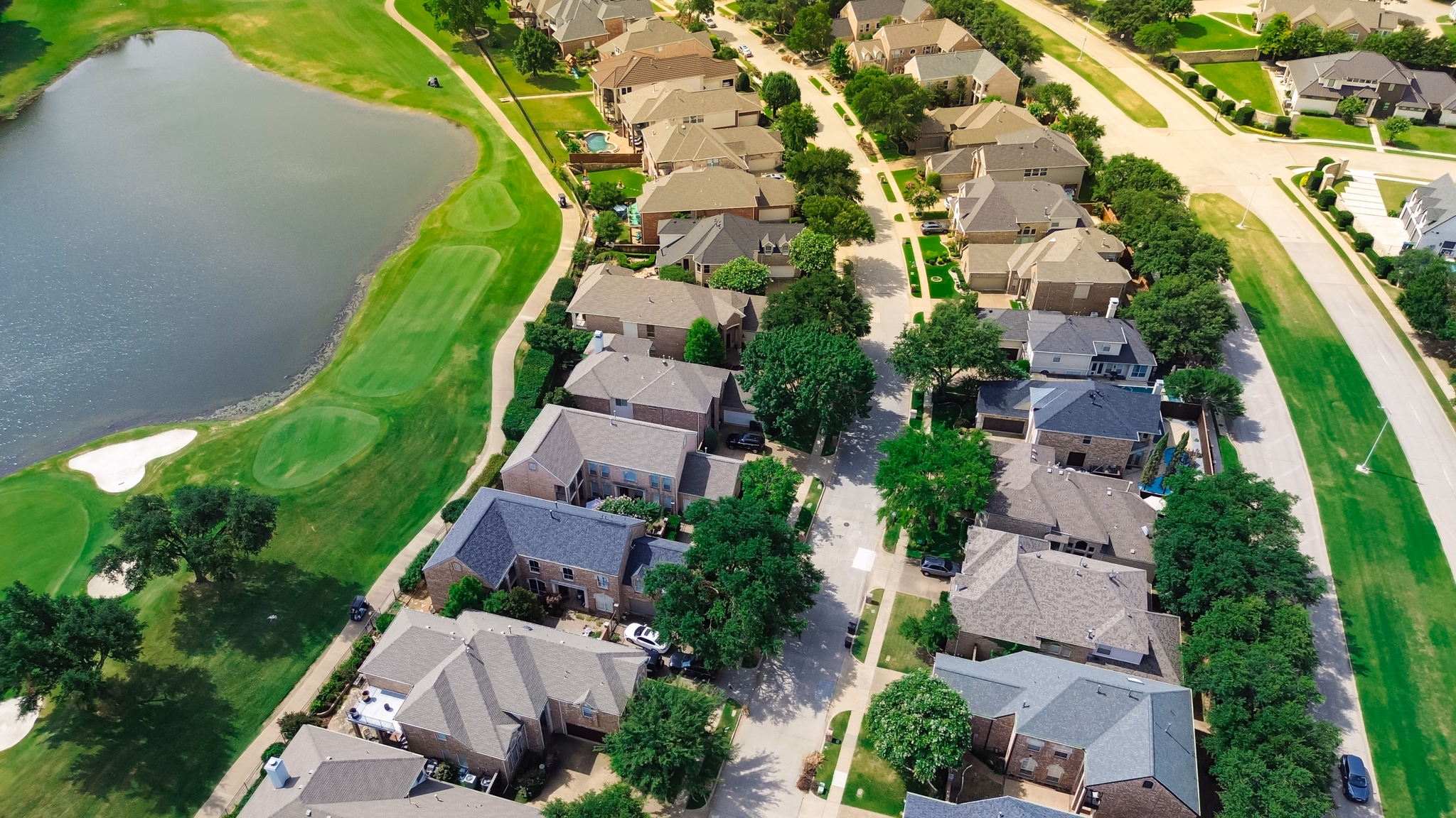 Aerial view of Fairway Bend neighborhood in Texas, showcasing houses, trees, and a nearby pond.