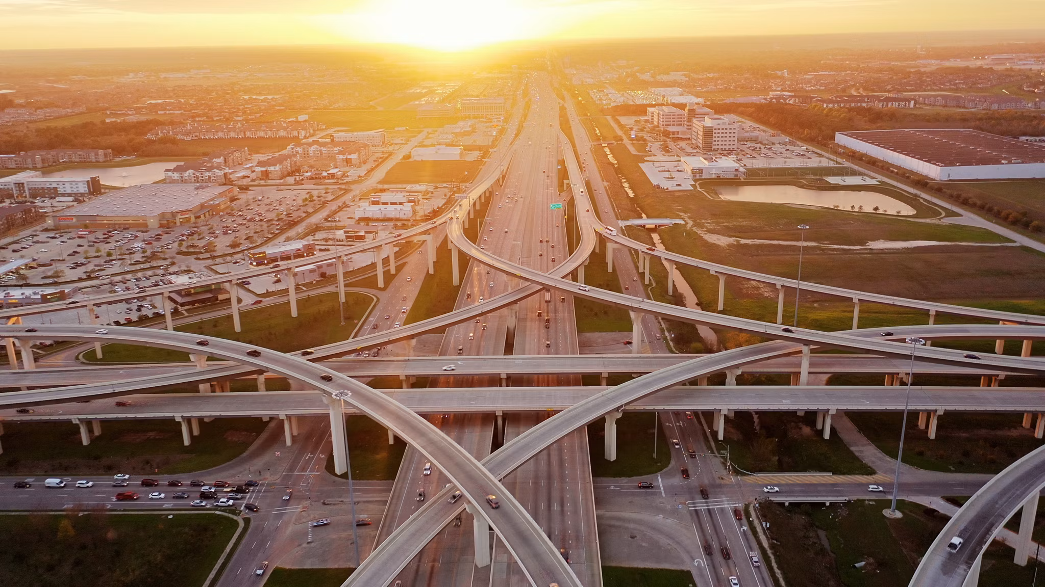 Aerial view of highways and roads in Katy, Texas, during sunset with buildings and greenery in the background.