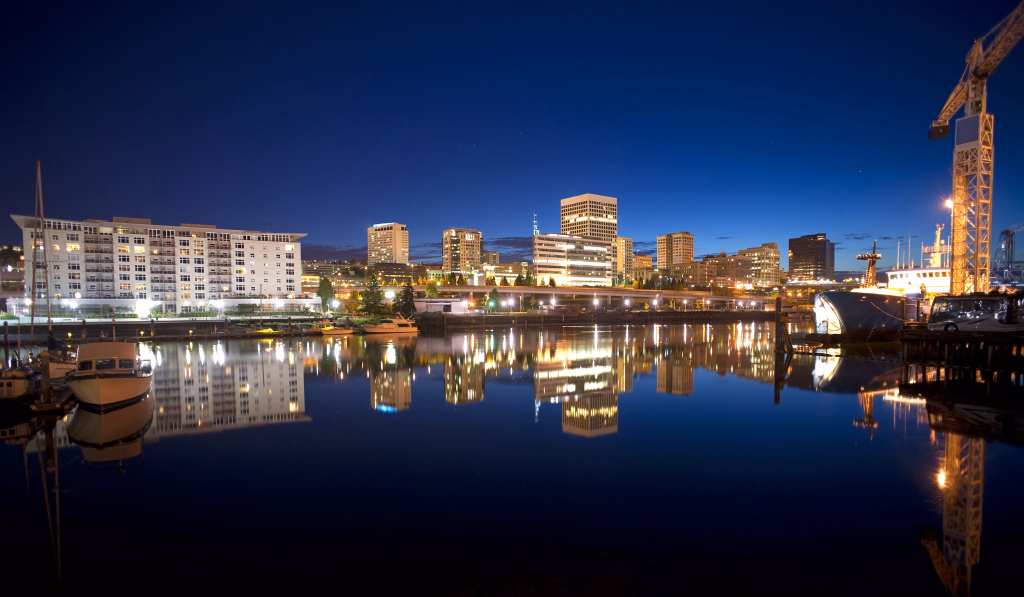 Night falls behind the Tacoma skyline and boats on Thea Foss Waterway