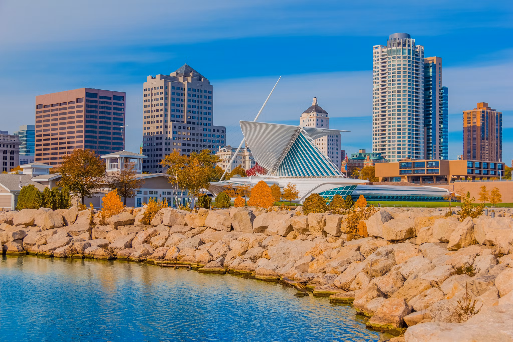Skyscrapers fill the skyline of Milwaukee and Lake Michigan, WI. The rock breakwater forms a protective barrier against the water.