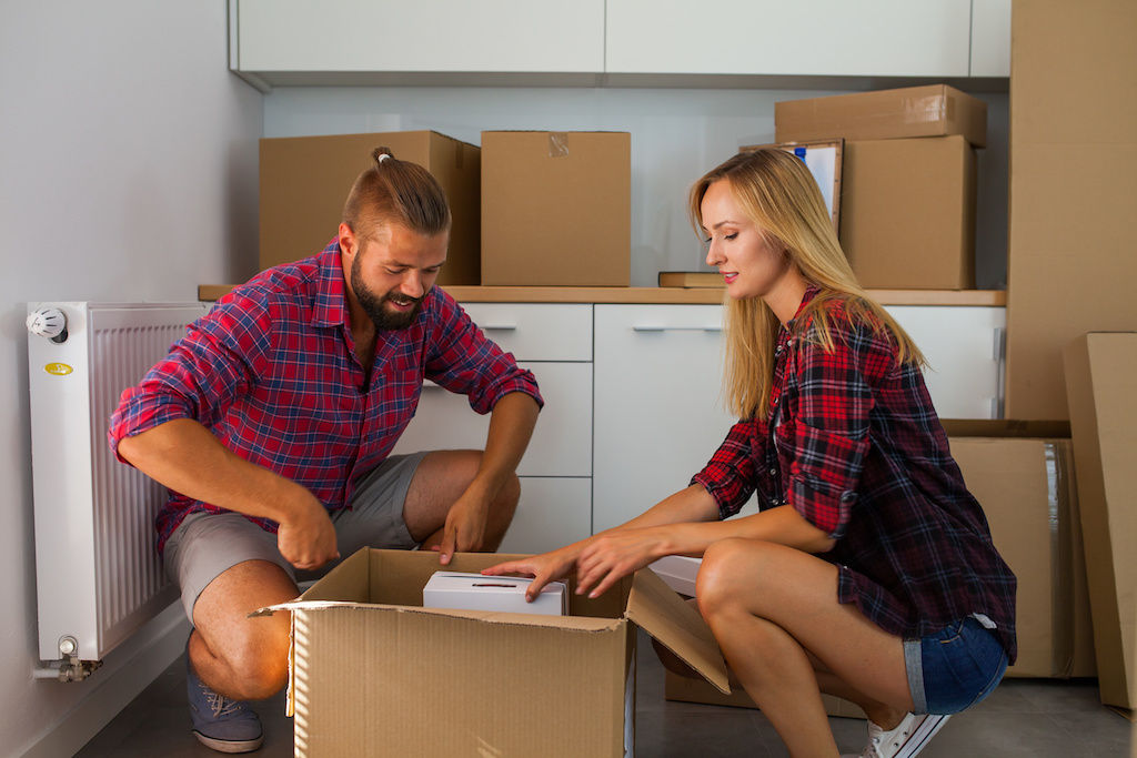Couple unpacking boxes in apartment kitchen