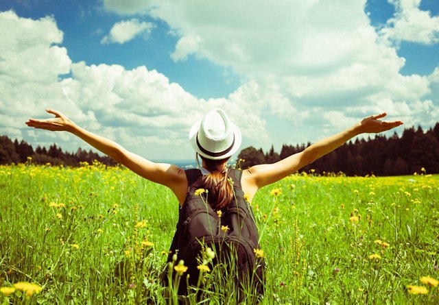 Woman with outstretched arms in a sunhat enjoying freedom in a vibrant wildflower field.