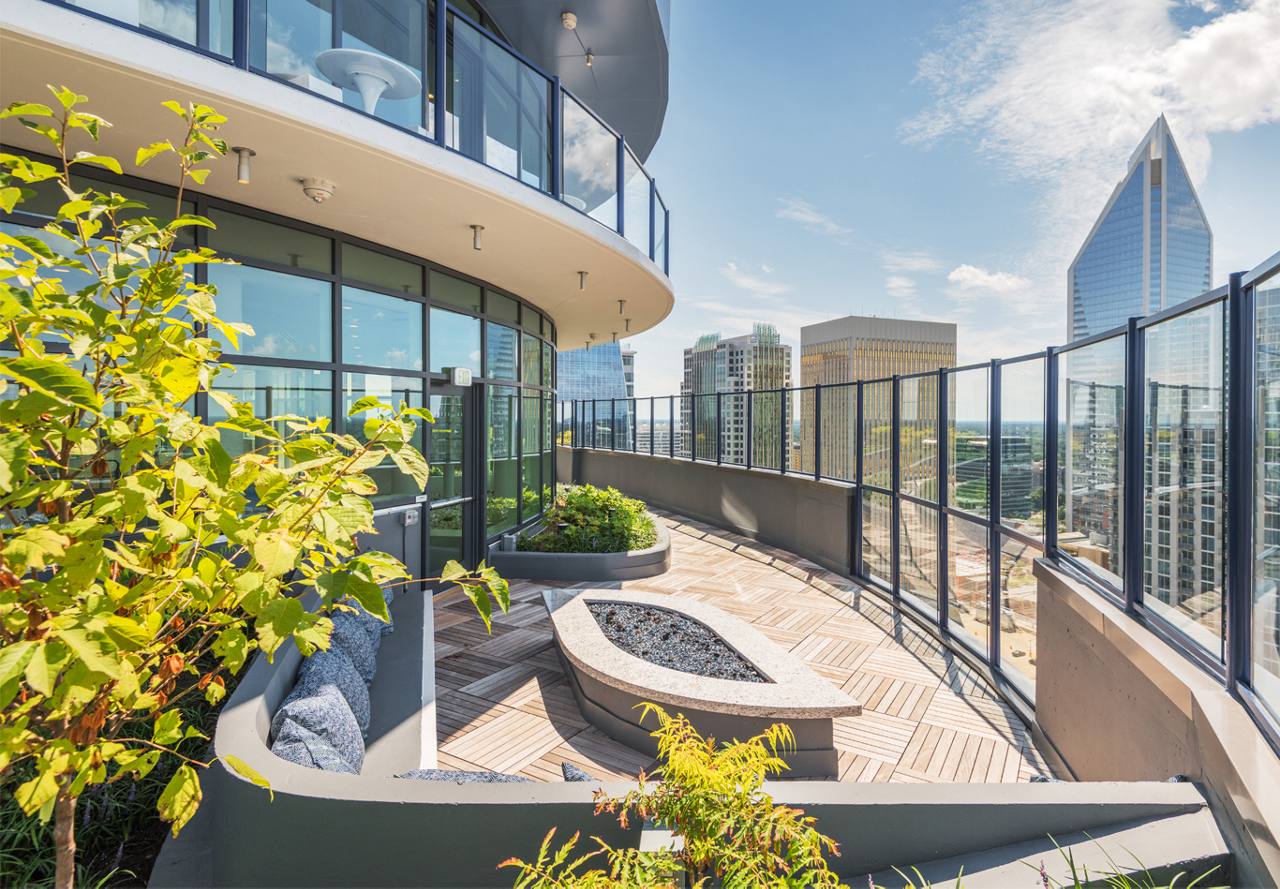 Modern rooftop garden terrace with wooden flooring and urban skyline views.