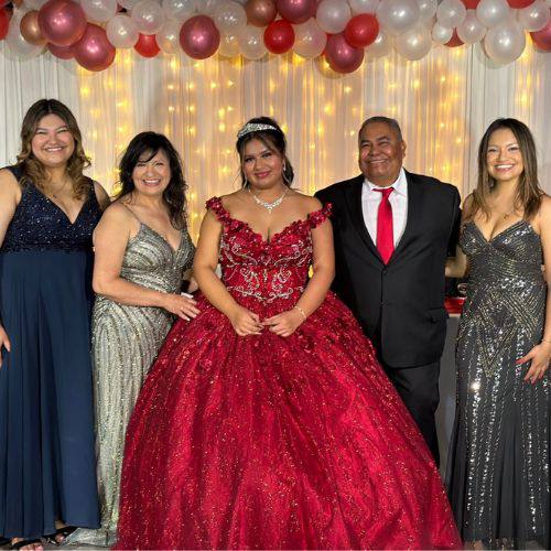 Rocio Simon, Management Coordinator and family, dressed in formal attire posing together, with a young woman in a red gown at the center, celebrating a special occasion.