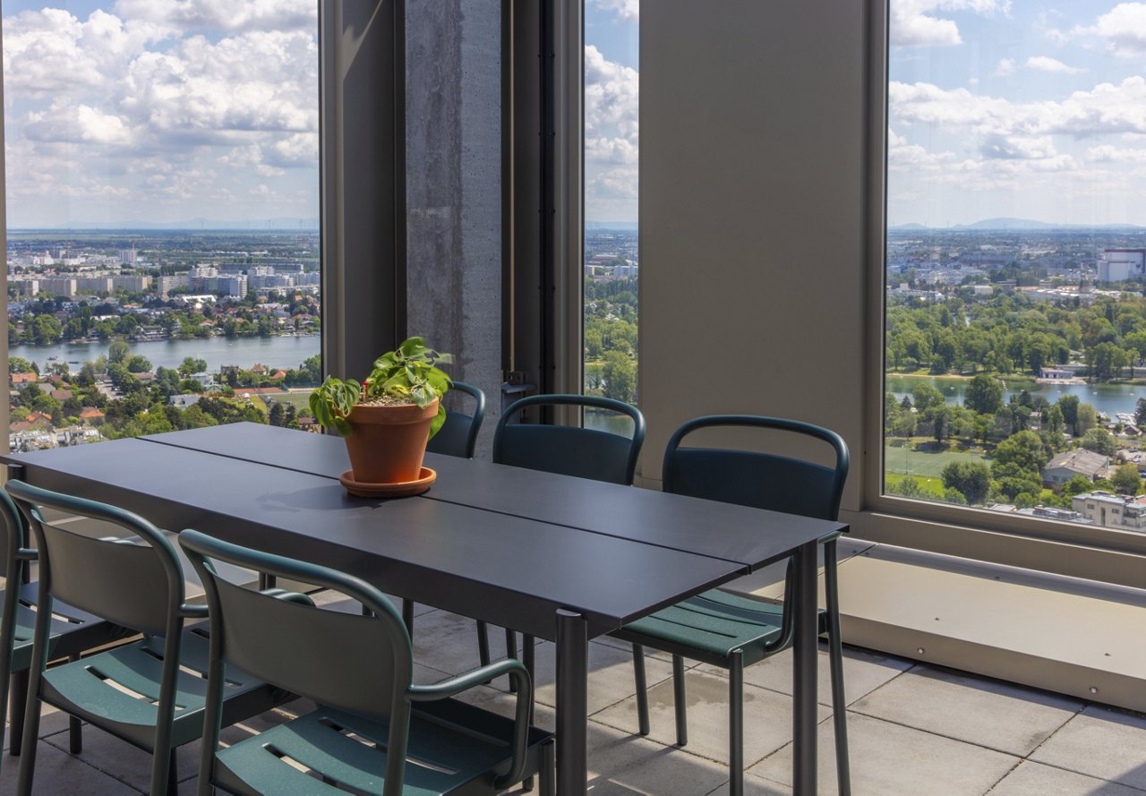 Indoor dining area with a large window offering a panoramic view of a cityscape and river