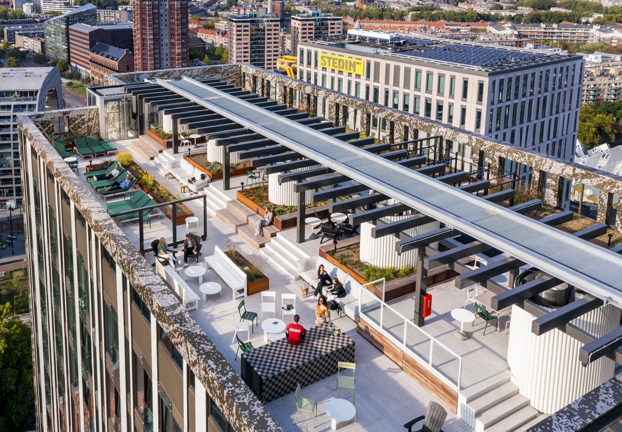 Aerial view of an urban rooftop garden with lounge areas and pergolas, surrounded by city buildings.