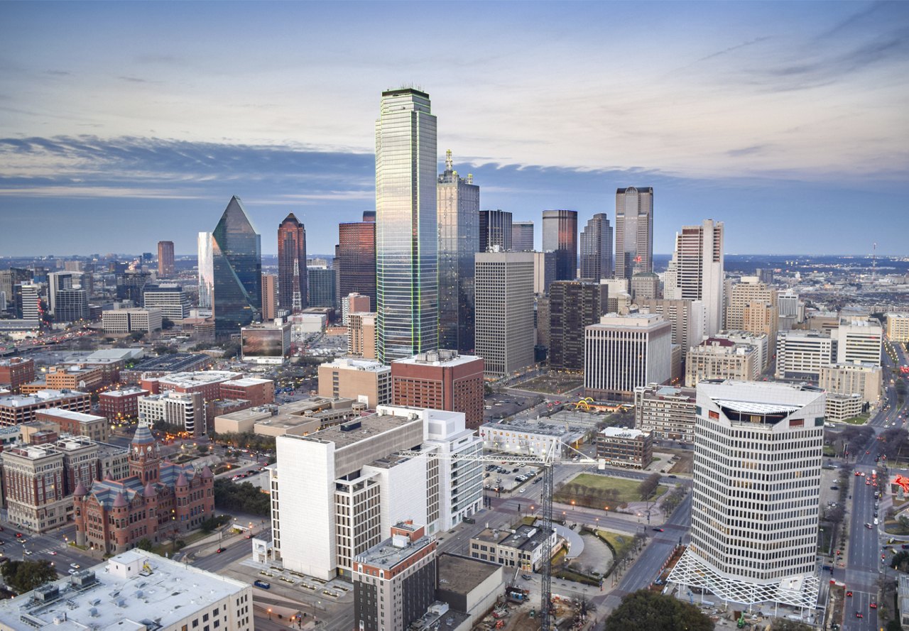 Scenic cityscape of Dallas featuring a vibrant sky with clouds and a diverse skyline of buildings at various heights.