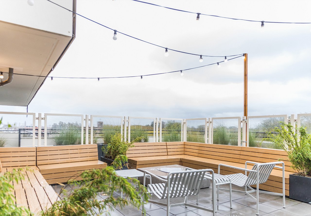 Outdoor rooftop space atop an apartment building in Europe, adorned with hanging string lights and plants, adding a touch of nature to the setting.