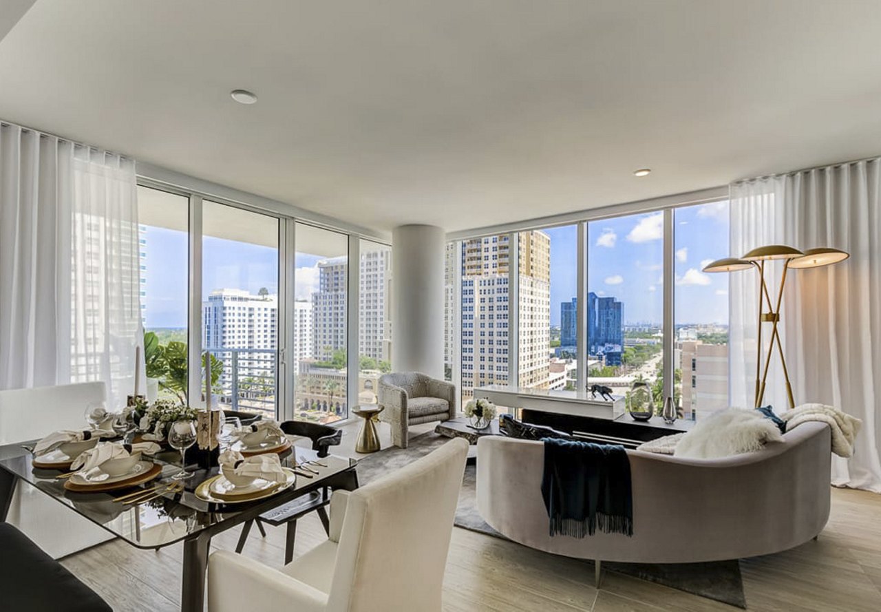 Elegant modern dining and living room with floor-to-ceiling windows offering a panoramic city view.