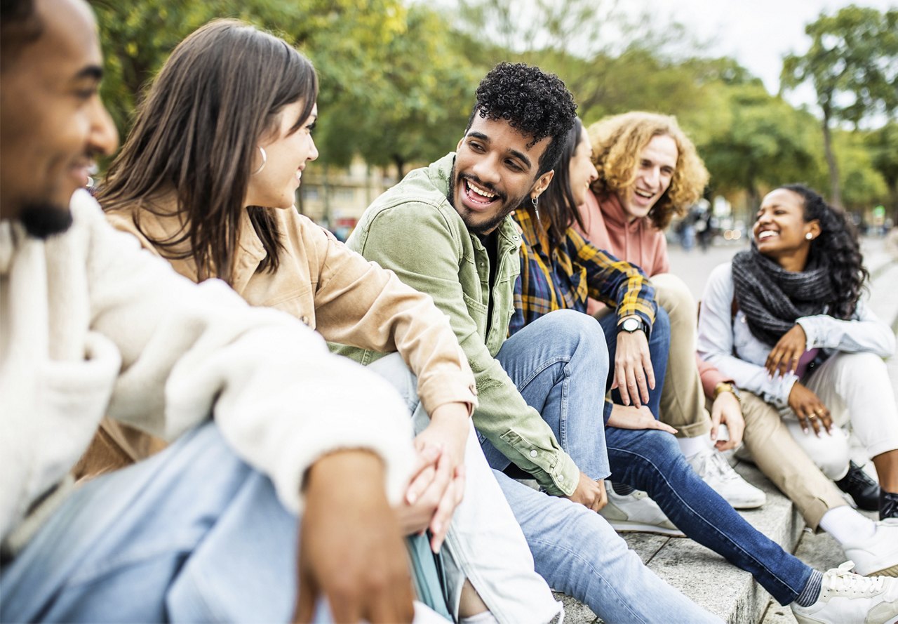 Diverse group of friends sitting on outdoor steps while enjoying each other's company