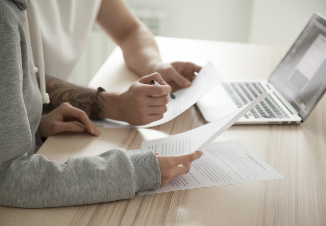 People looking a paperwork on table with computer