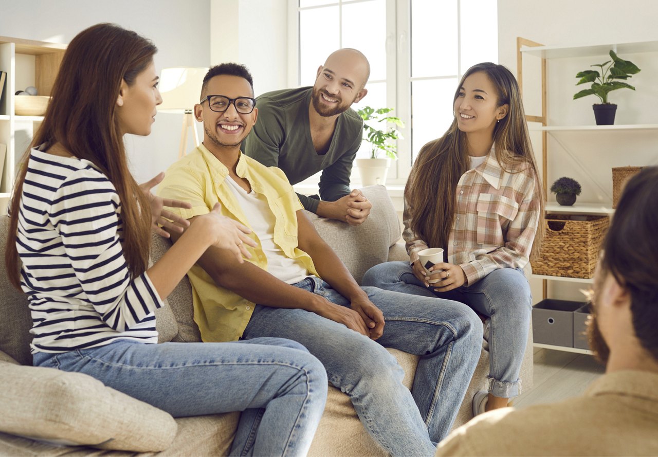 Friends sitting in apartment living room smiling and having conversation