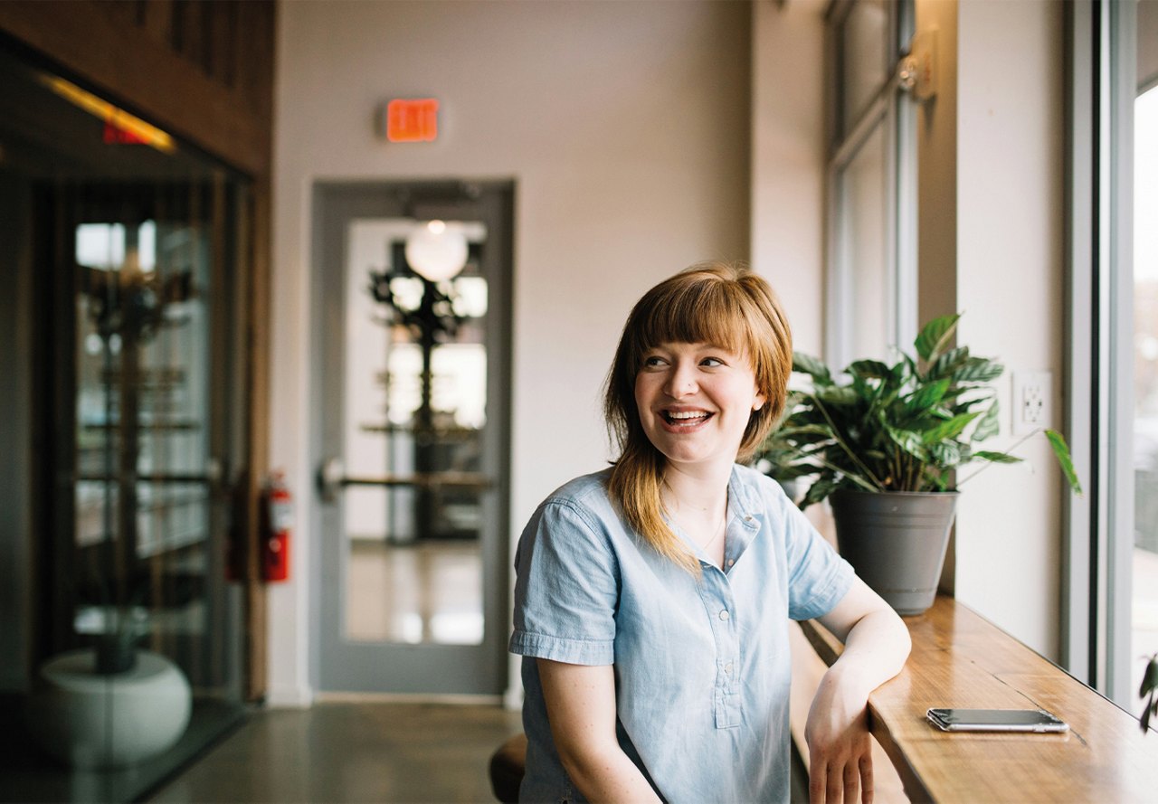 Woman looking behind her while sitting at wooden bar in apartment common area