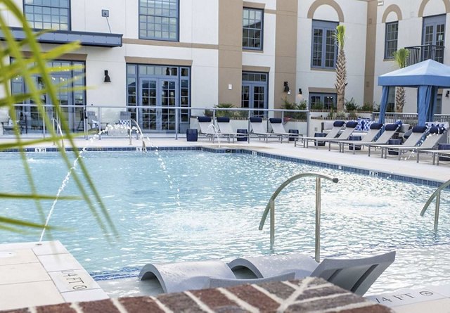 Pool area at apartment complex with lounge seating and palm trees