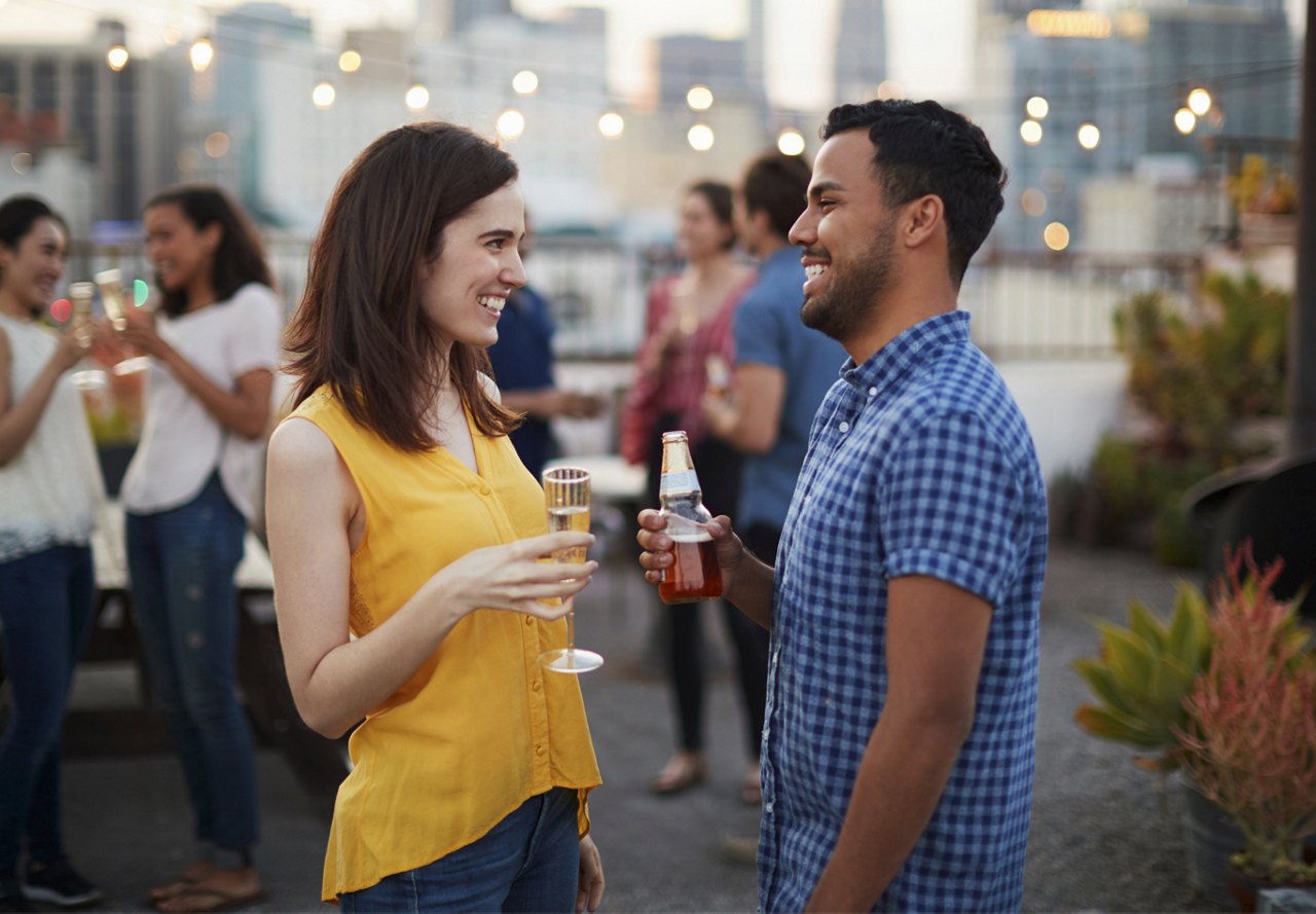 Man and woman enjoying drinks at community event on the rooftop