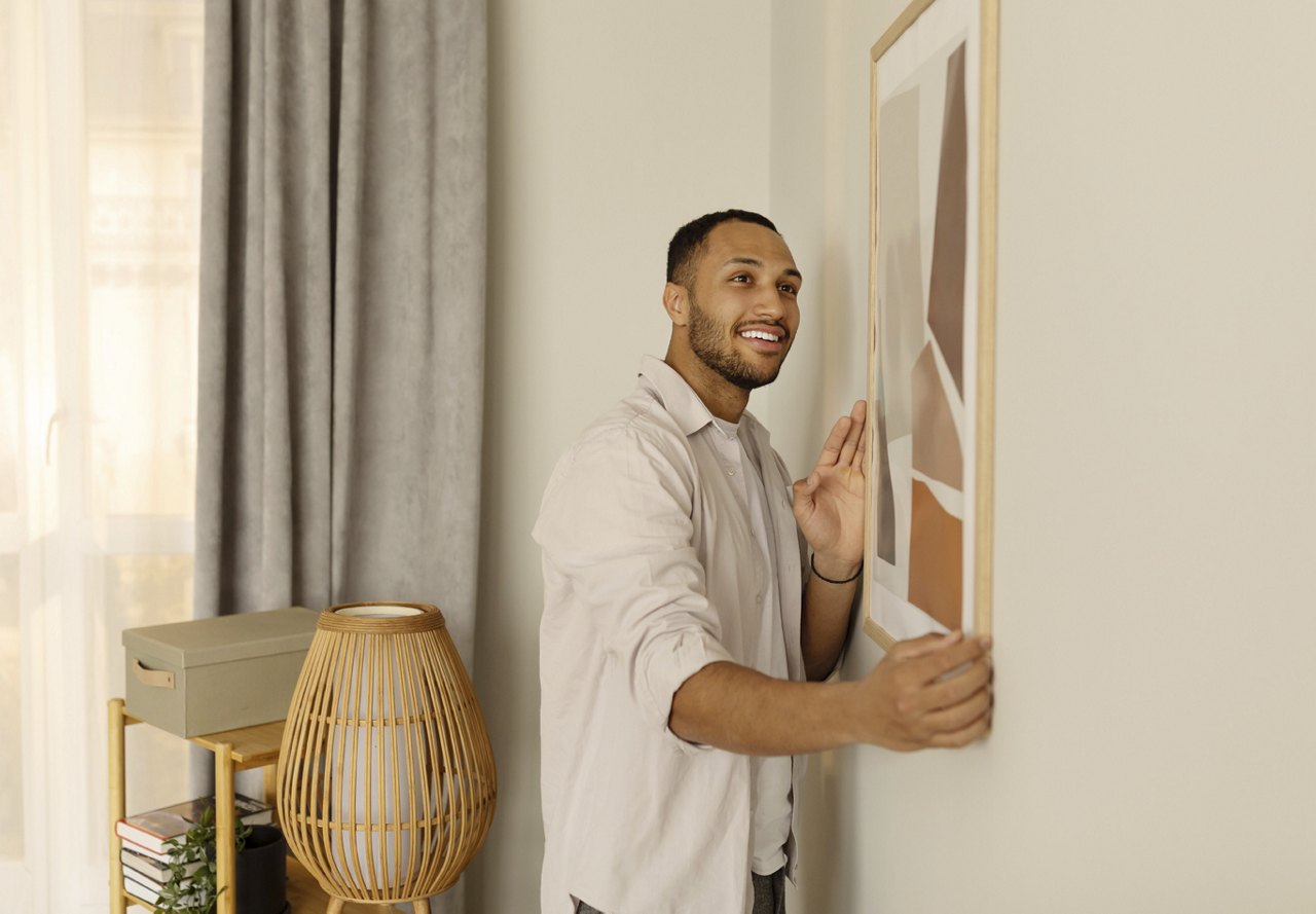 Man holding up artwork and hanging on wall as decoration