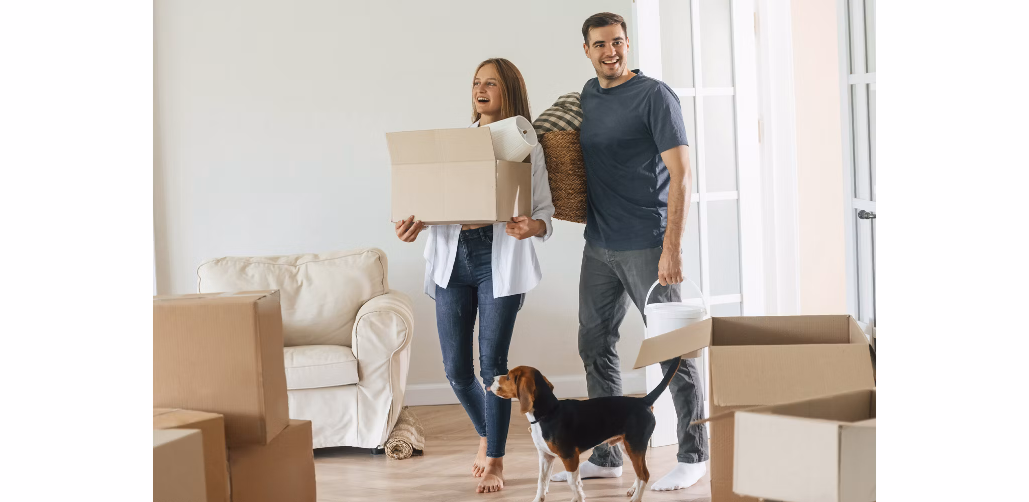 Young couple walking into new apartment for the first time with their dog holding boxes