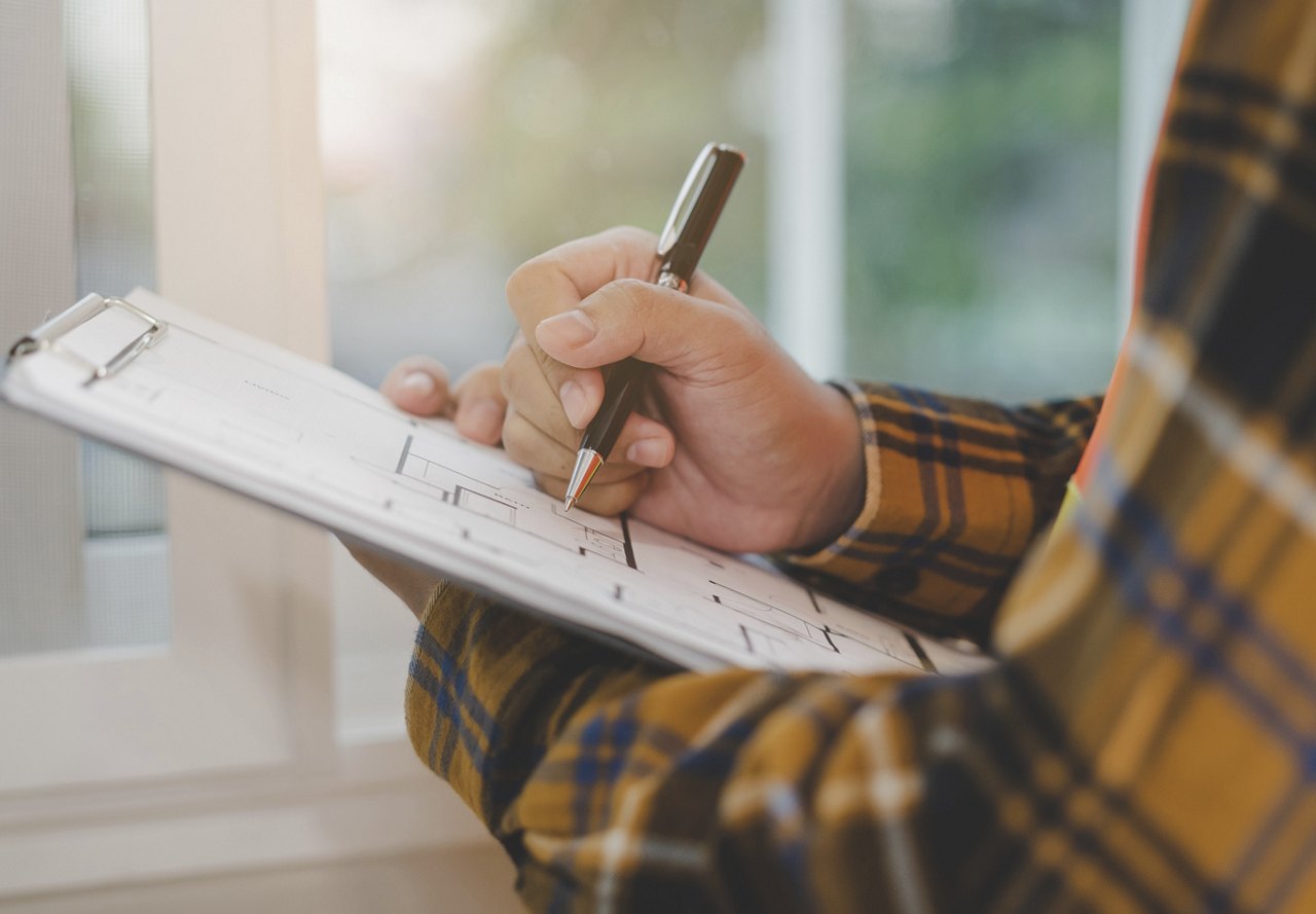 Man filling out inspection document with yellow plaid shirt on