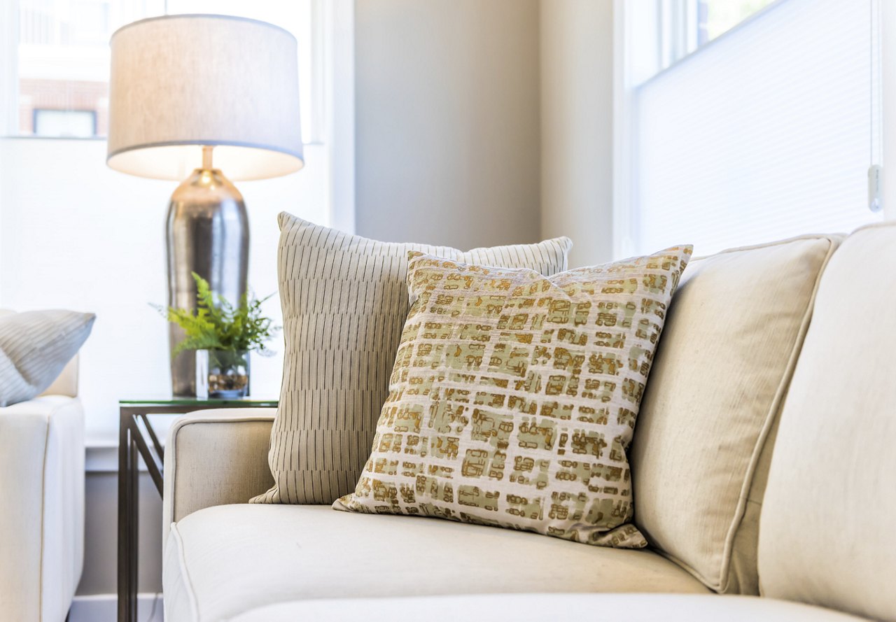 Neutral couch with throw pillows and lamp in the background