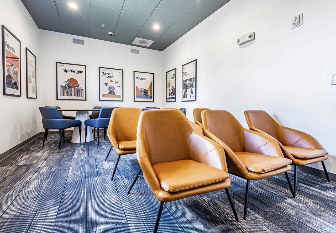 Movie theater area in apartment building with brown leather chairs and movie posters in the background