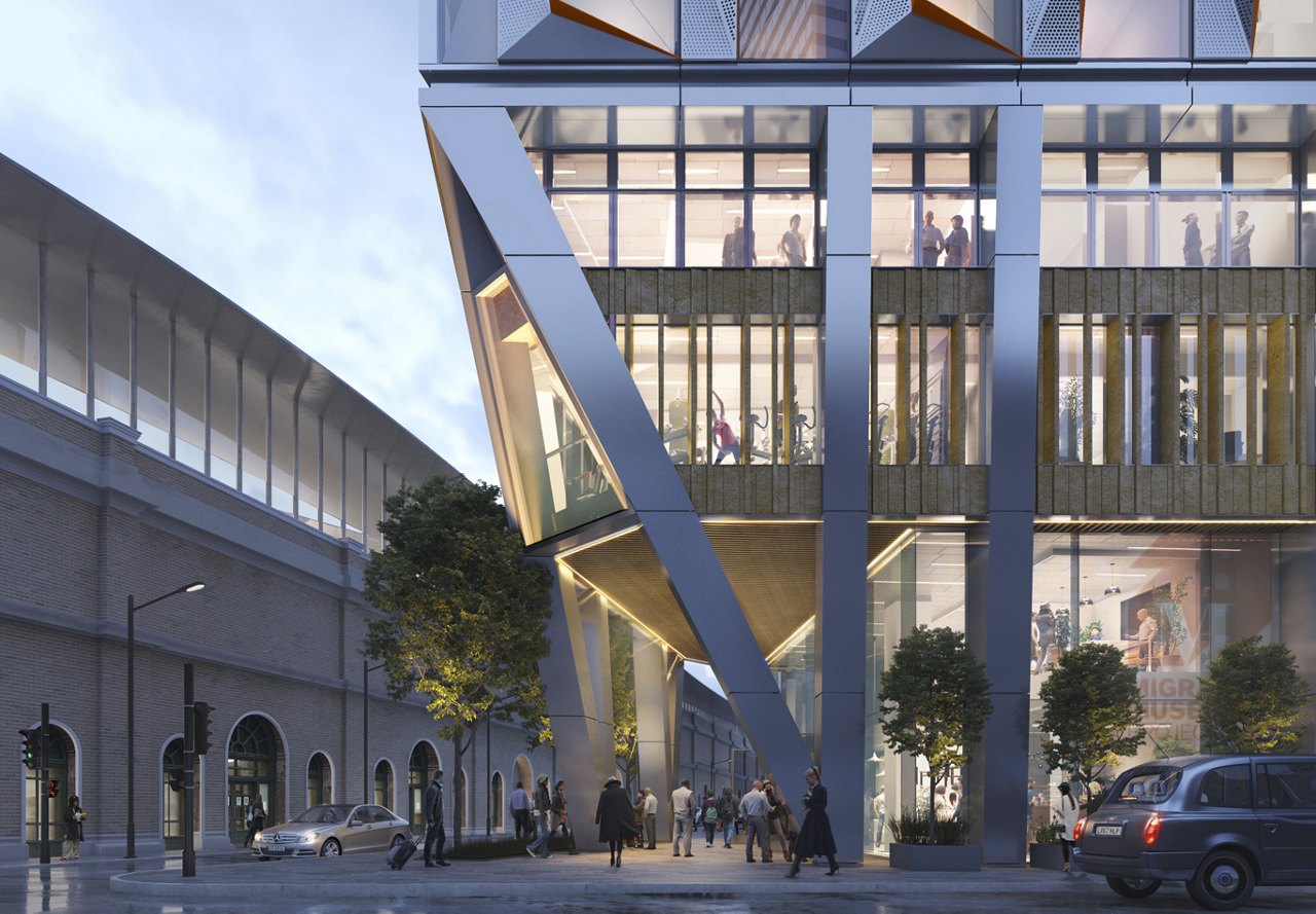 Twilight view of a modern building with geometric architecture, pedestrians, and vehicles on the street.