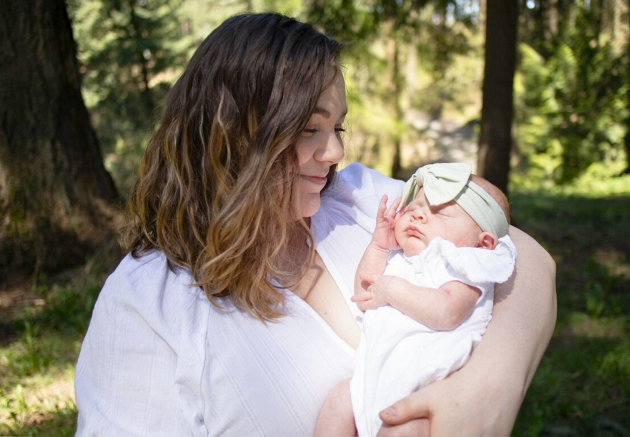 A woman lovingly cradles a newborn baby in a peaceful outdoor setting.