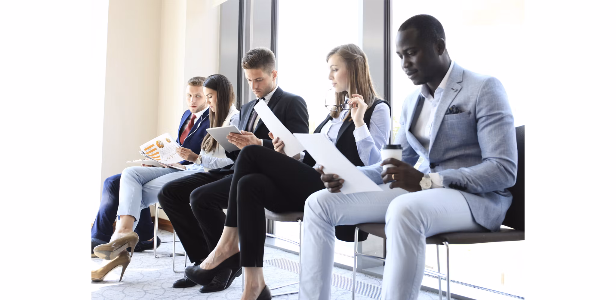young professionals waiting to go into interview reviewing resume