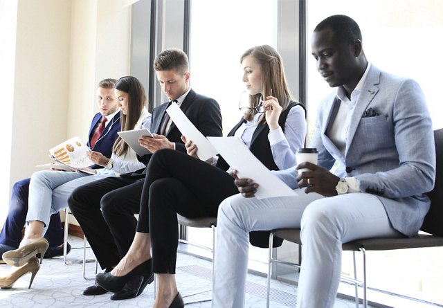 young professionals waiting to go into interview reviewing resume