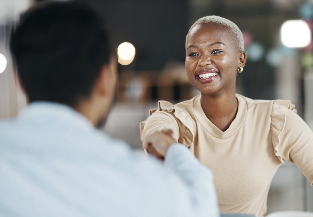 young woman shaking man's hand at the end of an interview with smile