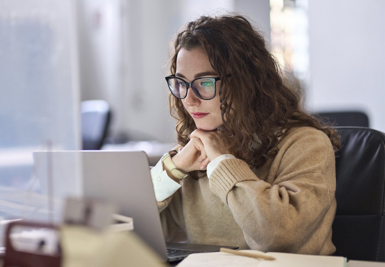 young woman doing research on computer with glasses