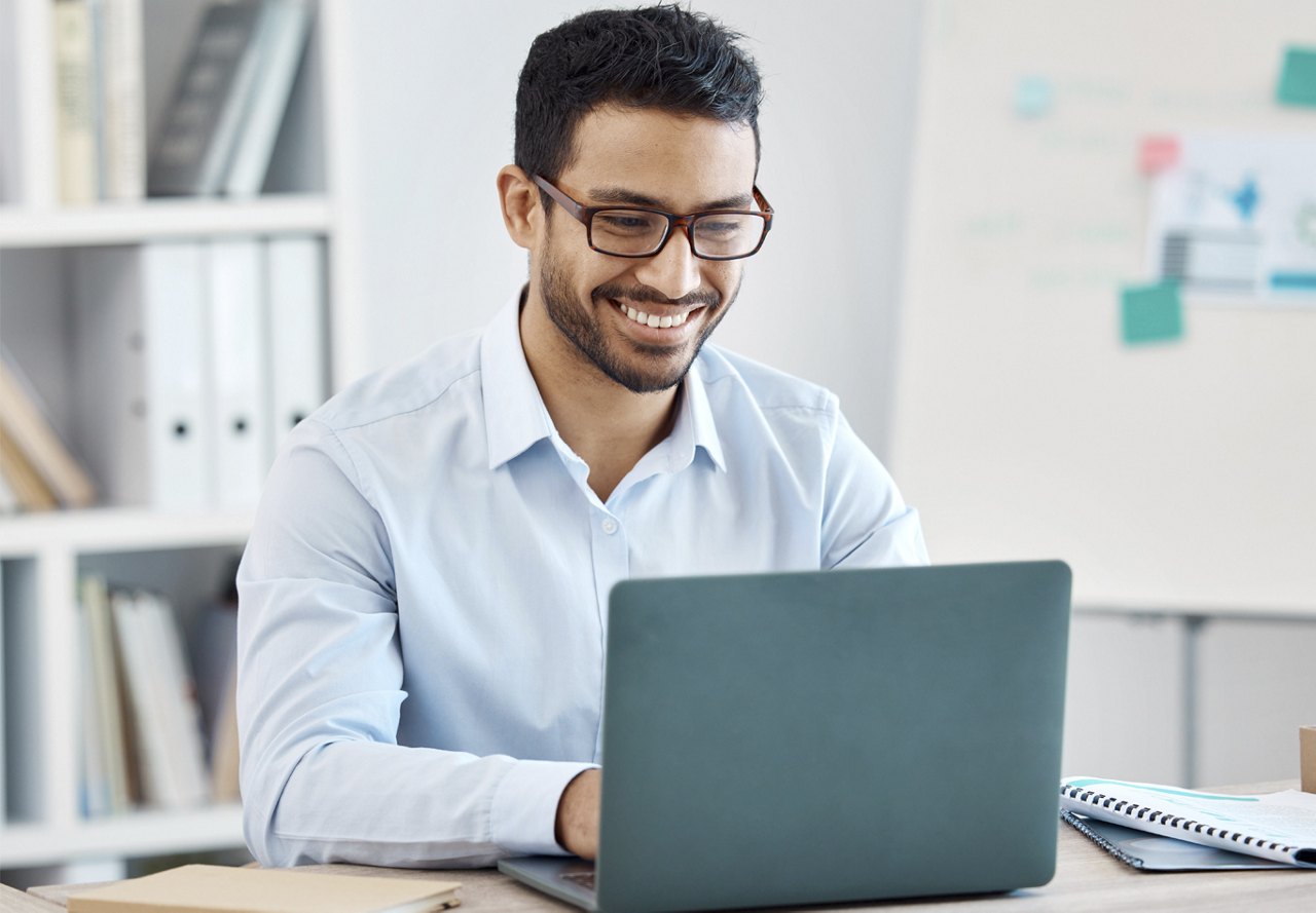 business man sending email on computer smiling in office