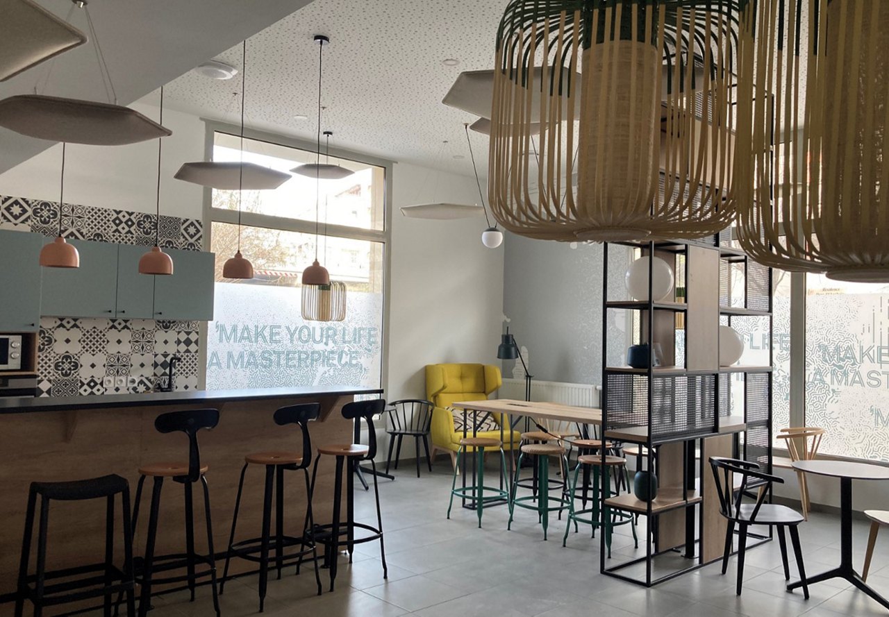 Modern student lounge with a bar and the text 'Make your life a masterpiece' on the window.