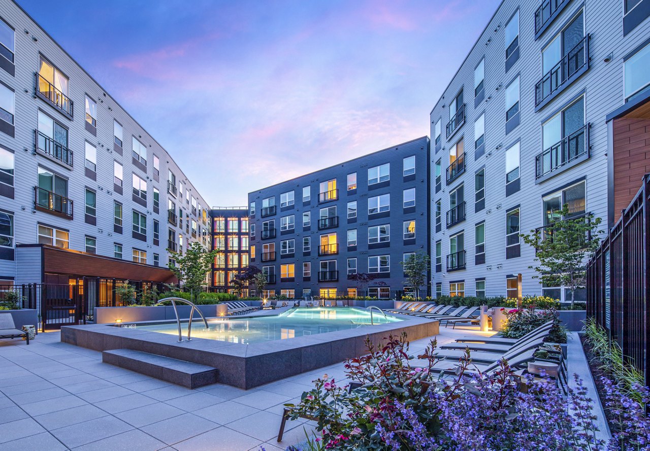 Evening view of an apartment complex with a pool.