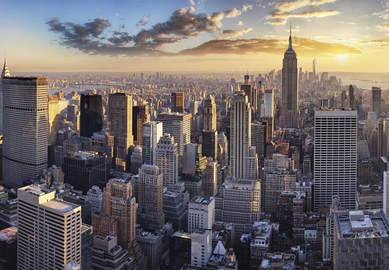 A breathtaking view of New York City at sunset, with the sky ablaze in warm colors and towering skyscrapers stretching across the skyline.