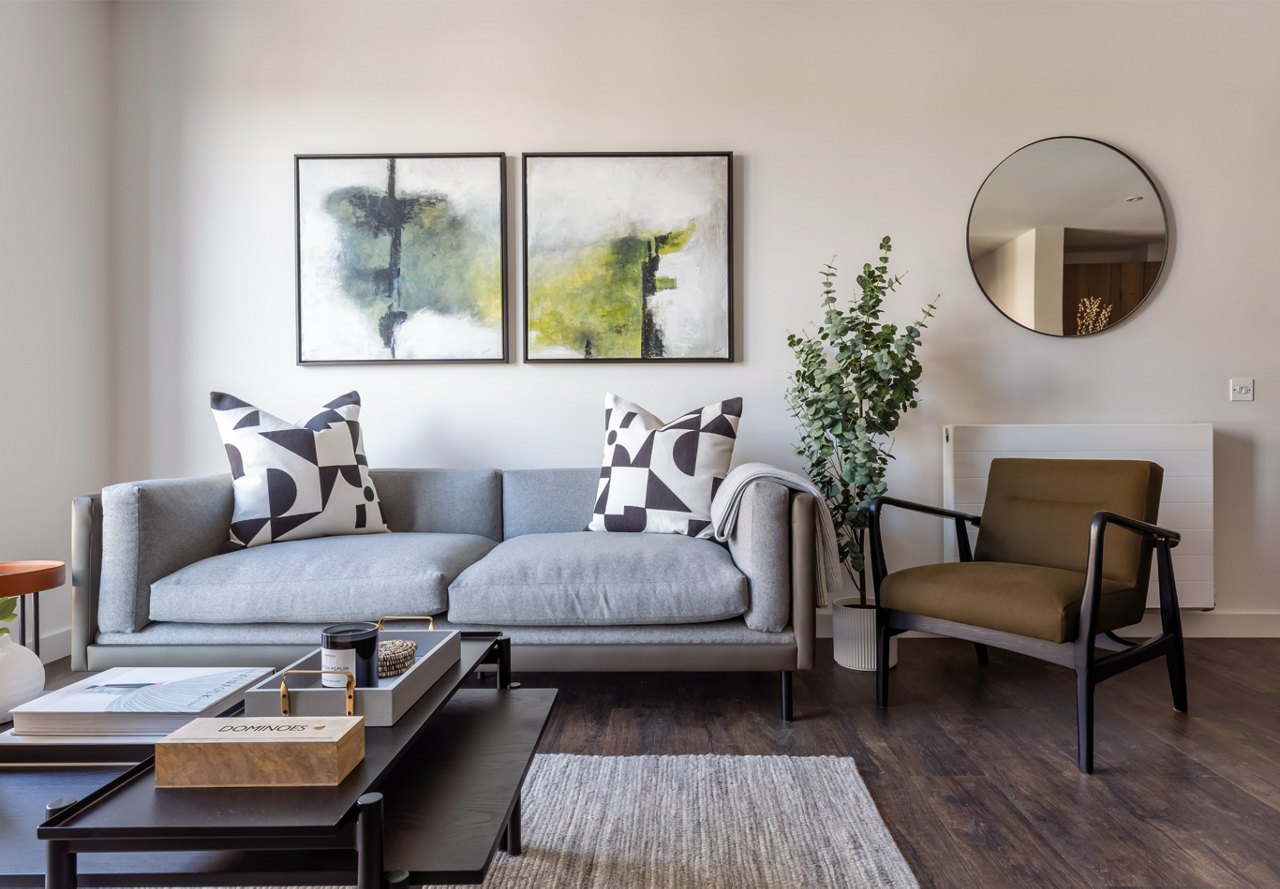 Modern living area in an apartment complex featuring a mirror on the wall, artwork above the couch, and unique design elements that add personality and style to the space.