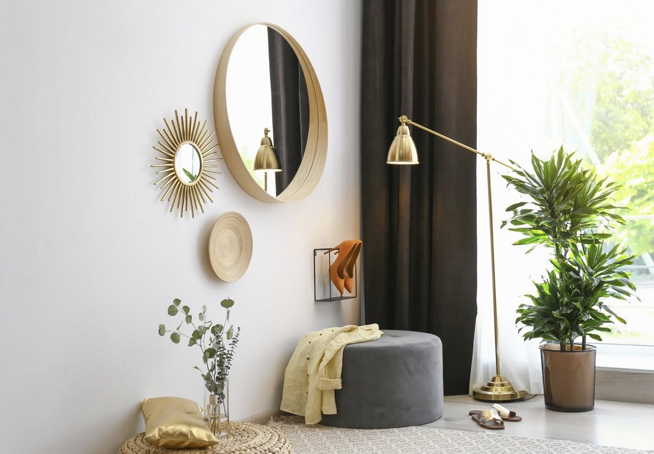 Cozy corner in an apartment with several mirrors hanging on the walls, complemented by dark accents that balance the brightness of the decor and the large window beside the space.