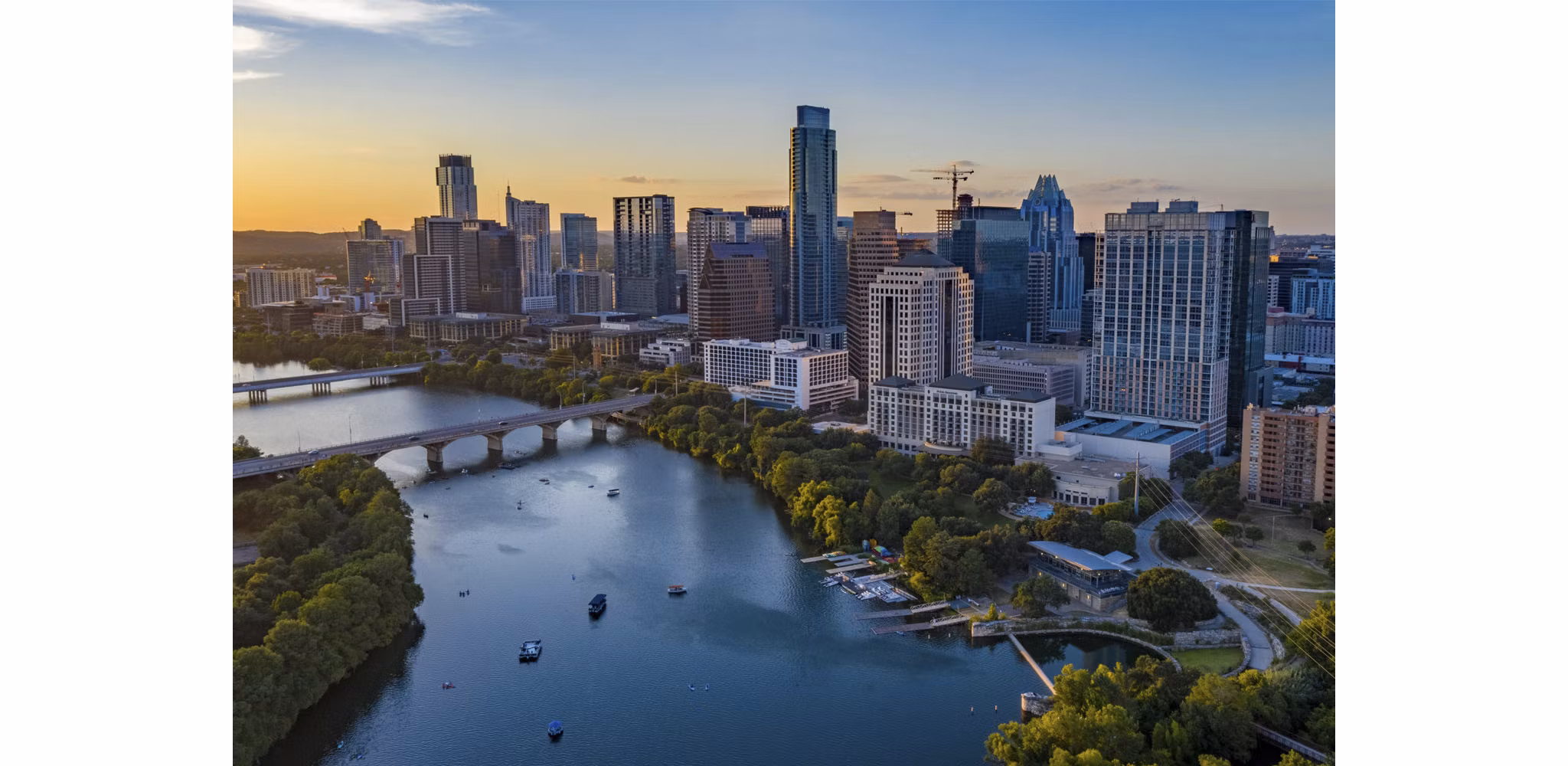 A stunning Texas city skyline reflected in a nearby body of water, set against a vibrant blue and orange sunset.