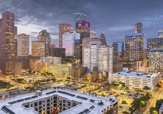 A cityscape of Houston in the evening, illuminated by a myriad of lights from the buildings and cars below. The dark sky provides a dramatic backdrop, highlighting the vibrant energy and bustling activity of the city.