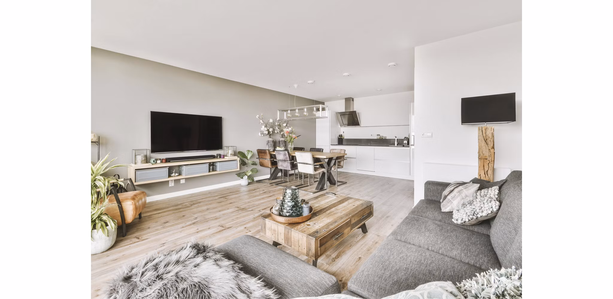 A modern studio apartment featuring neutral finishes, showcasing the living area and kitchen, with plants and decorative items enhancing the space.