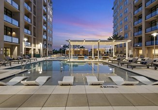 Apartment community in Houston, Texas, featuring a modern pool with ample seating for residents, overlooking a beautiful sunset in the background.