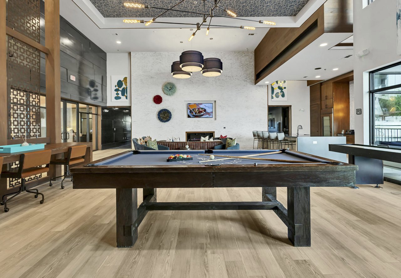 A modern common area in an apartment community featuring a pool table and artistic decorations. The vibrant decor and engaging design elements create an inspiring and lively space for residents to relax and socialize.