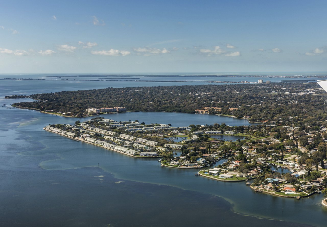 Aerial view of St. Petersburg, Florida, showcasing a mix of water and land in the distance, with homes visible and a clear sky in the background.