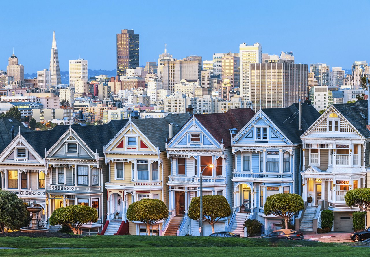 A view of San Francisco showcasing the iconic Painted Ladies homes in the foreground, with the city skyline and scenic cityscape in the background.