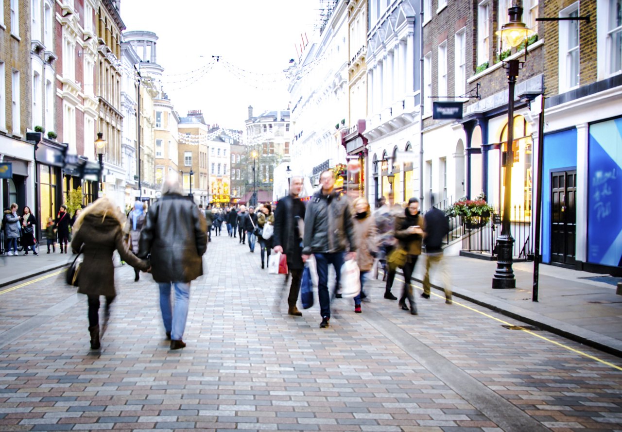 A bustling city street in an urban area, filled with people shopping and enjoying their day, capturing the vibrant energy of the neighborhood.