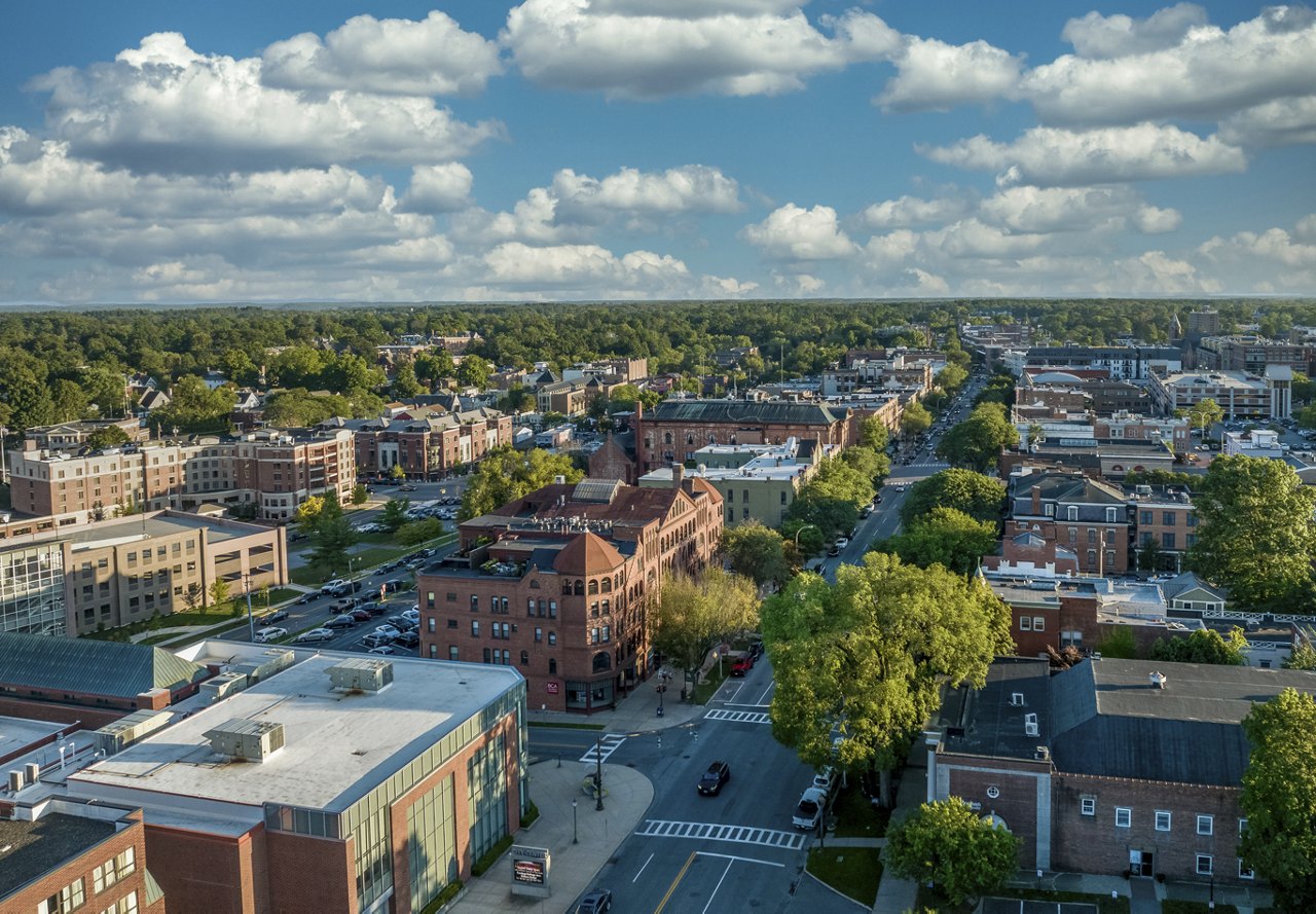 An aerial view of Saratoga Springs, New York, showcasing the city's buildings with tree-lined streets weaving through the neighborhood.